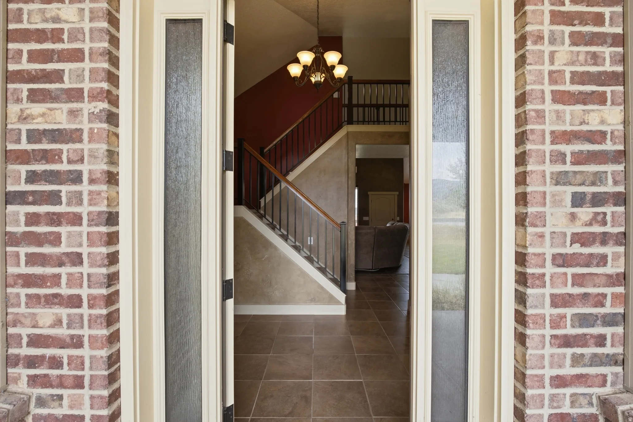 Entryway featuring brick-clad exterior columns and a substantial wood door with frosted glass sidelights
