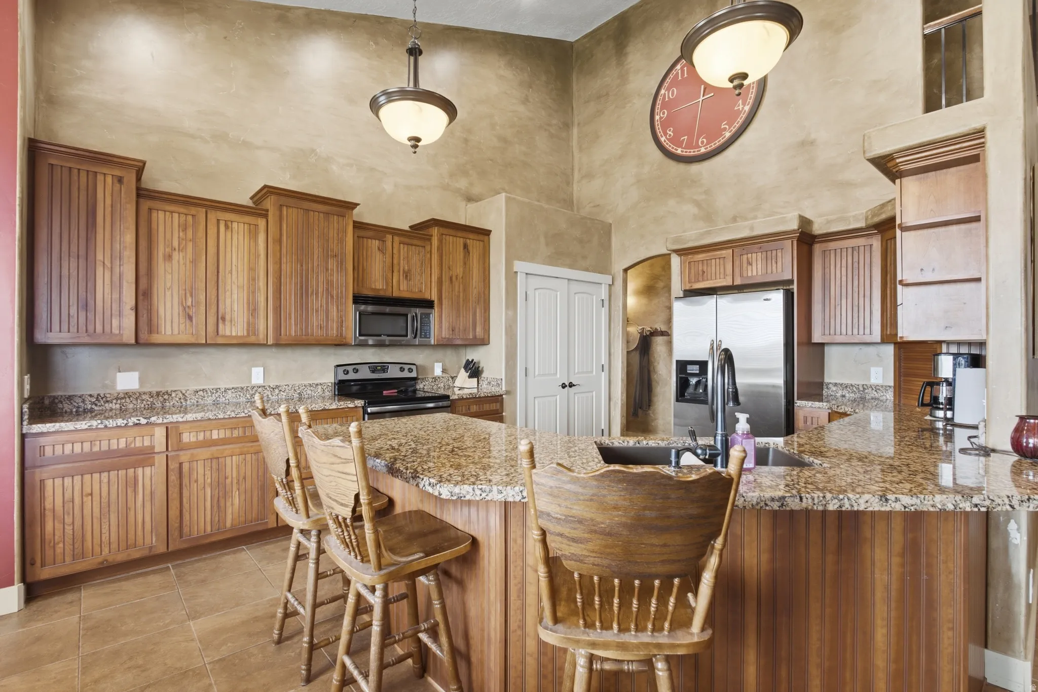 Kitchen featuring a center island with bar seating, wood-finish cabinetry, speckled granite countertops, and stainless-steel appliances