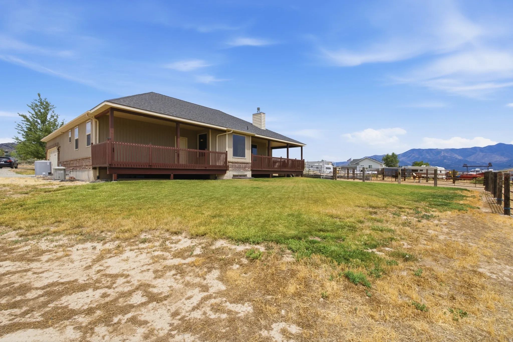 Ranch-style residence featuring a covered deck, perimeter fencing, and a mountain backdrop