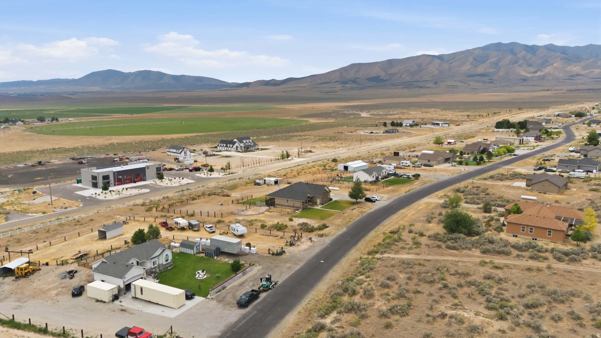 Aerial perspective showcasing a residential street with diverse home styles, set against a backdrop of mountains and expansive open land