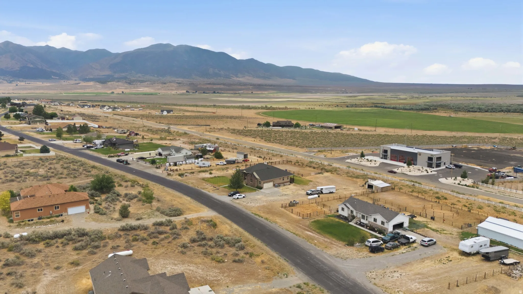 Expansive rural landscape featuring distant mountains, open fields, and scattered residential properties