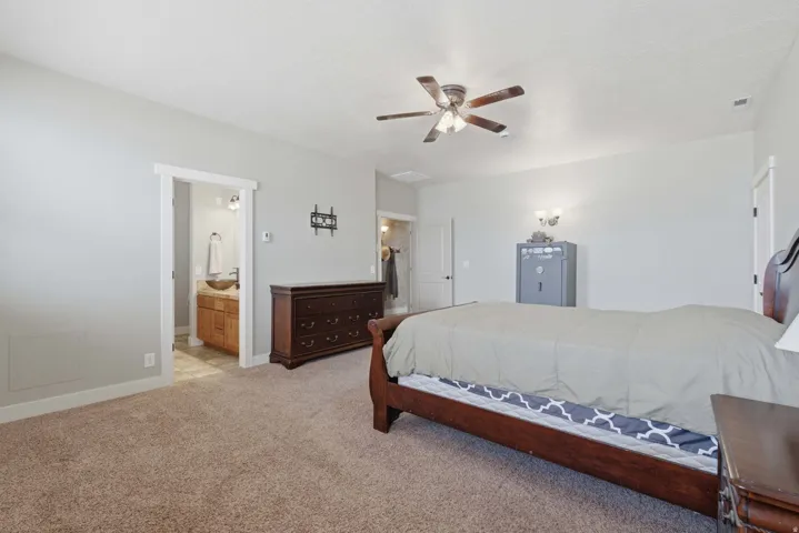 Carpeted bedroom with a ceiling fan, recessed lighting, and a doorway to an en-suite bathroom