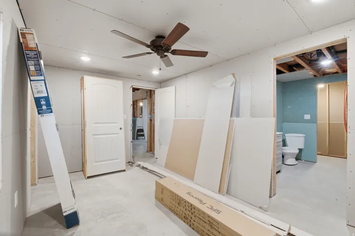 Unfinished room featuring a ceiling fan with light, recessed lighting, and a white interior door