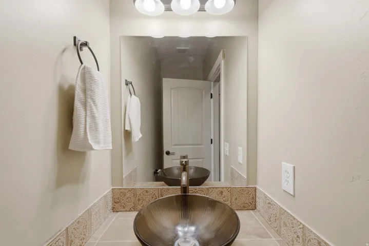 Bathroom vanity featuring a vessel sink, dark bronze faucet, and a large mirror