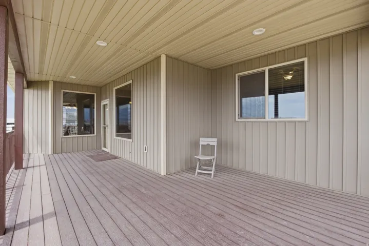 Covered outdoor deck with composite decking, recessed lighting, and vertical siding