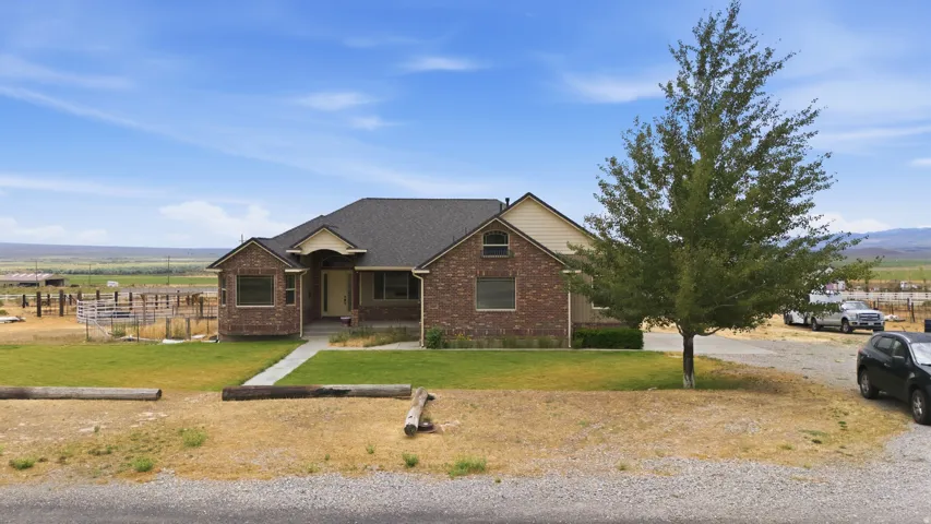 Ranch-style residence featuring a brick facade, dark shingle roof, and a covered front entry
