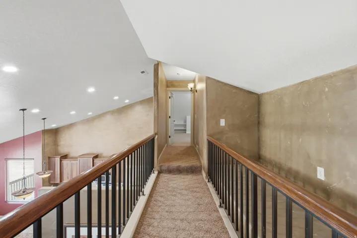Carpeted hallway with a dark wood and metal railing