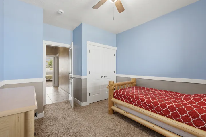 Carpeted room with a two-tone wall treatment, featuring a ceiling fan with light fixture and a built-in closet with double doors