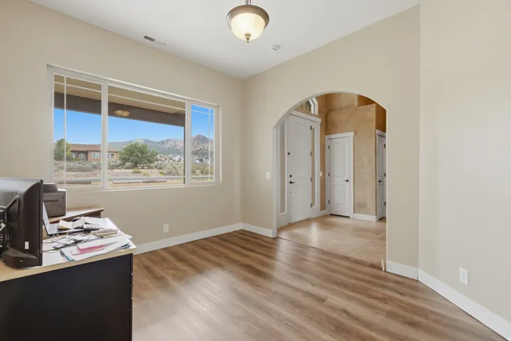 Neutral-toned room featuring a large window with mountain scenery, wood-finish flooring, and an arched entryway