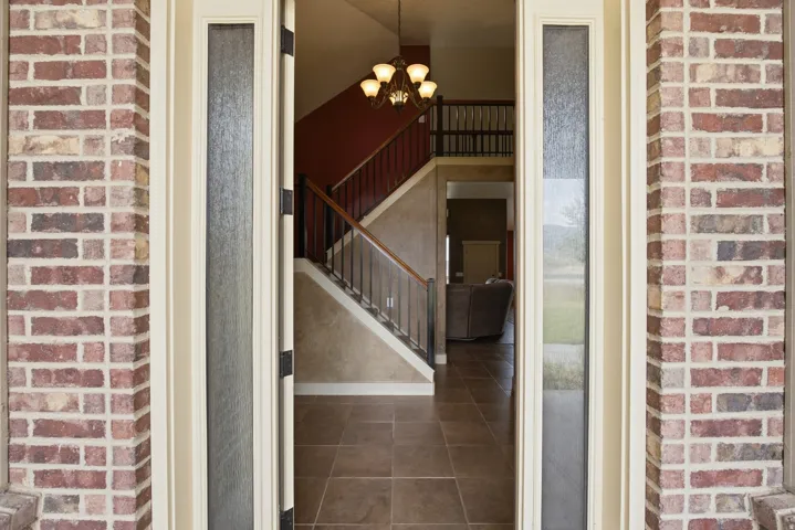 Entryway featuring brick-clad exterior columns and a substantial wood door with frosted glass sidelights