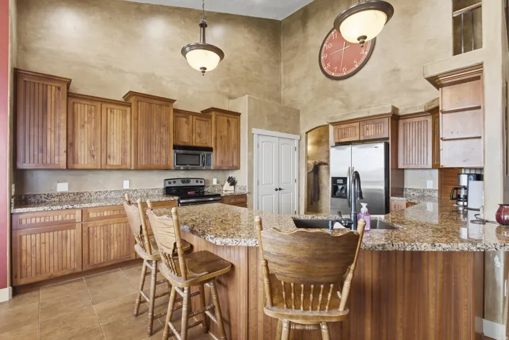 Kitchen featuring a center island with bar seating, wood-finish cabinetry, speckled granite countertops, and stainless-steel appliances