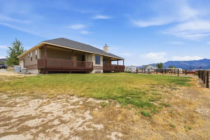 Ranch-style residence featuring a covered deck, perimeter fencing, and a mountain backdrop