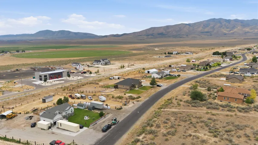 Aerial perspective showcasing a residential street with diverse home styles, set against a backdrop of mountains and expansive open land