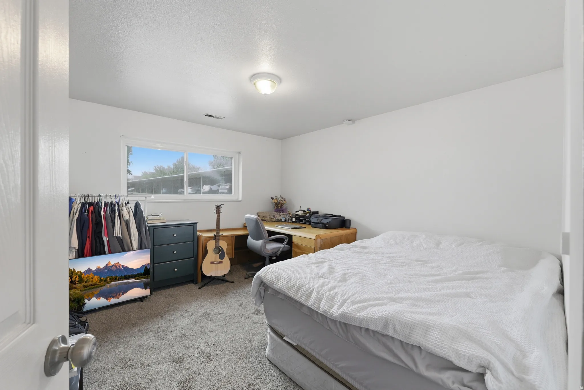 Carpeted room featuring a white ceiling and walls, a window with horizontal blinds, and a flush-mount ceiling light fixture