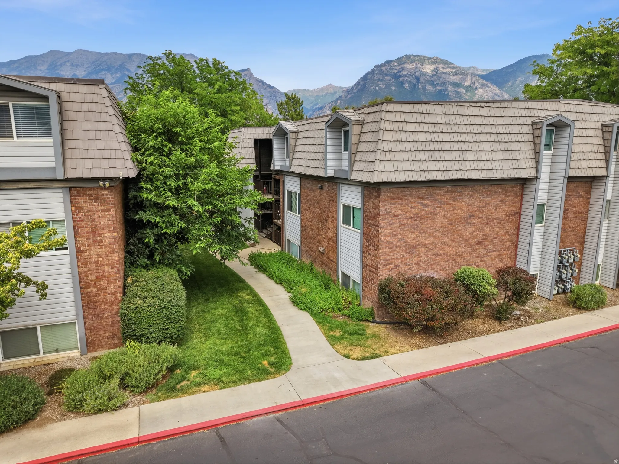 Multi-story residential buildings featuring brick and siding exteriors, dormer windows, and a shingled roof