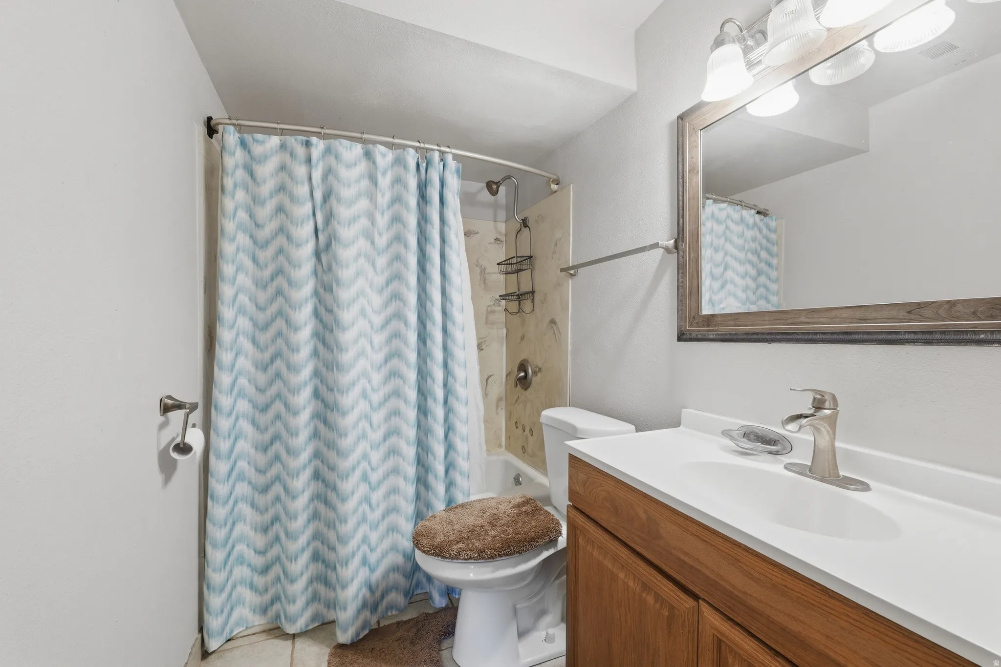 Bathroom featuring a single vanity with wood-finish cabinetry, a white countertop, and brushed nickel fixtures