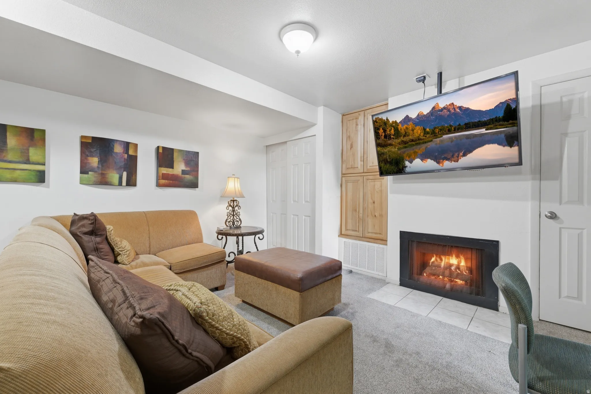 Recreational space featuring a built-in fireplace with a tile hearth, carpeted flooring, and built-in wood-finish cabinetry