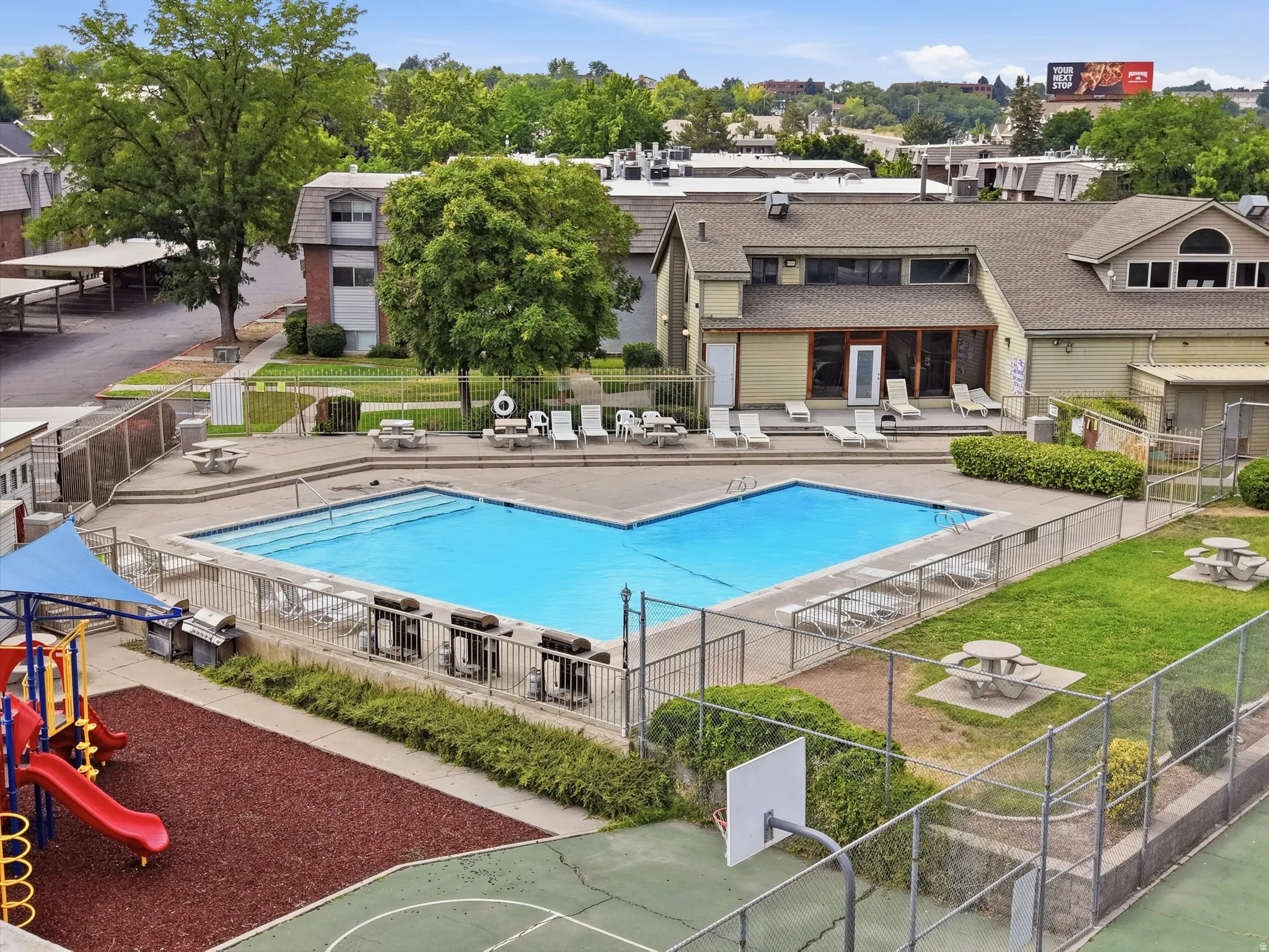 Central swimming pool surrounded by a concrete deck with lounge seating