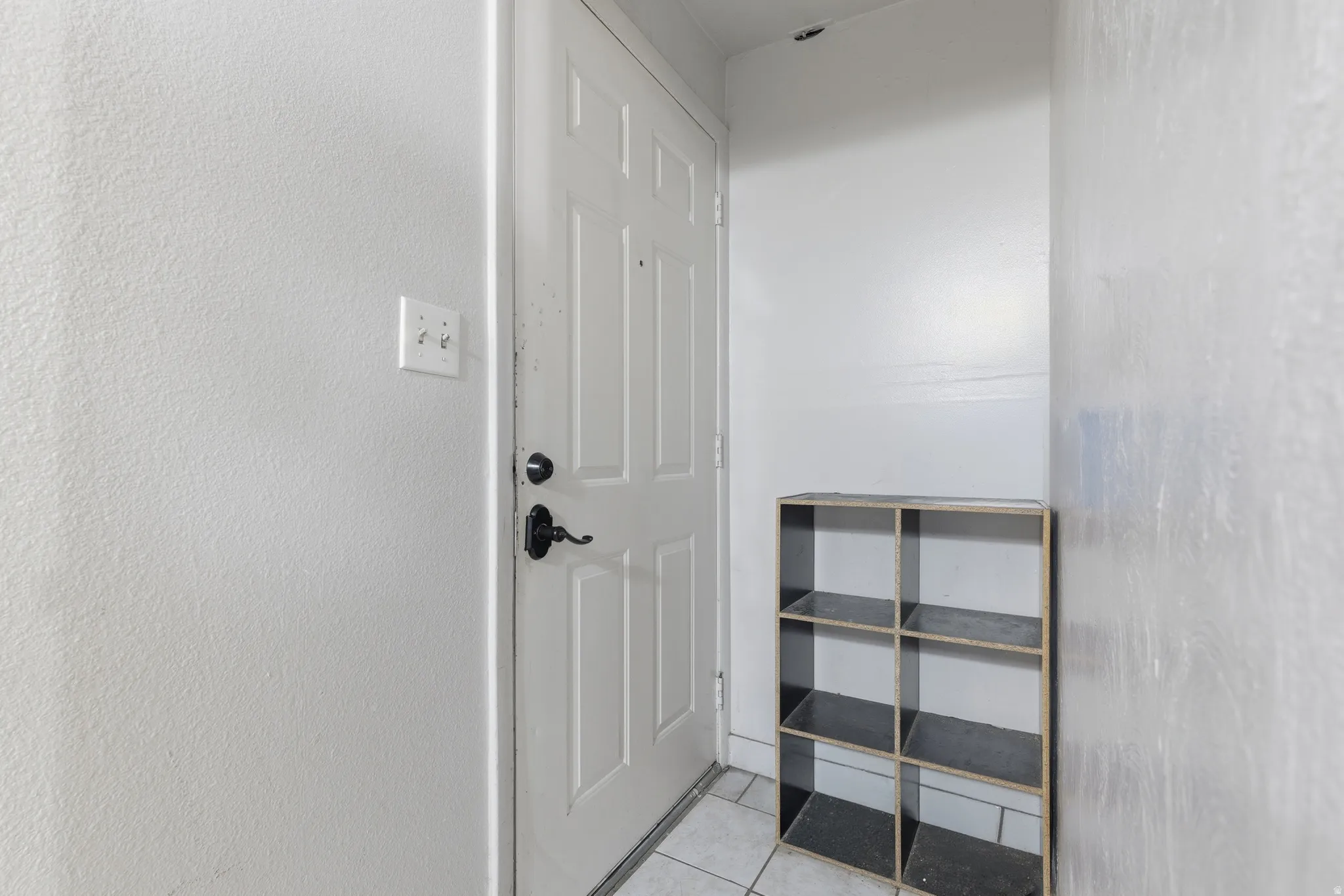 Entryway featuring a paneled door with dark hardware, light-colored walls, and tile flooring