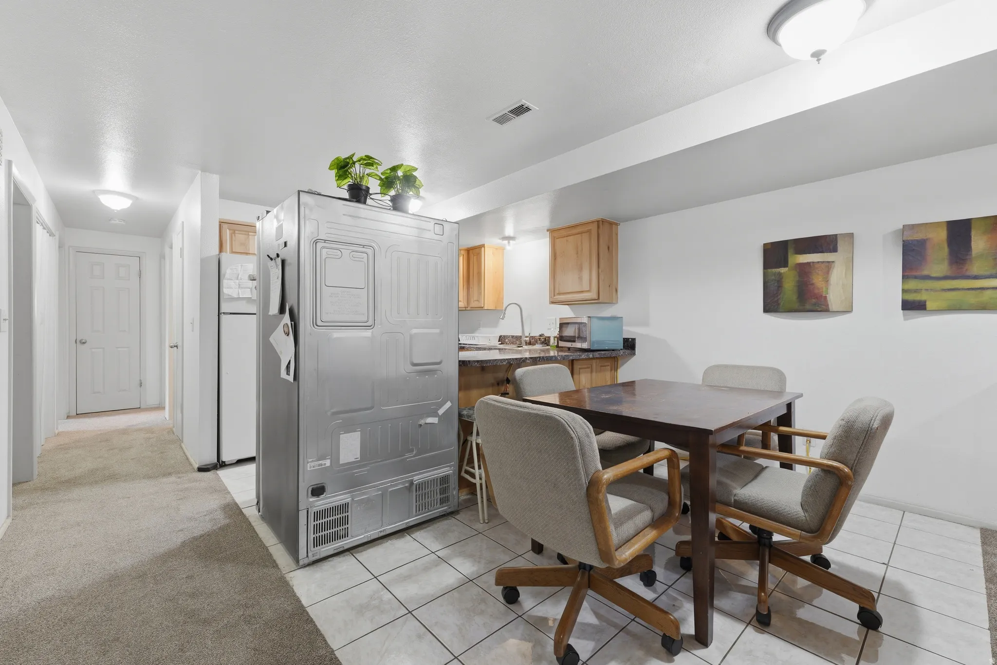 Kitchenette featuring wood cabinetry, dark countertop, and tile flooring