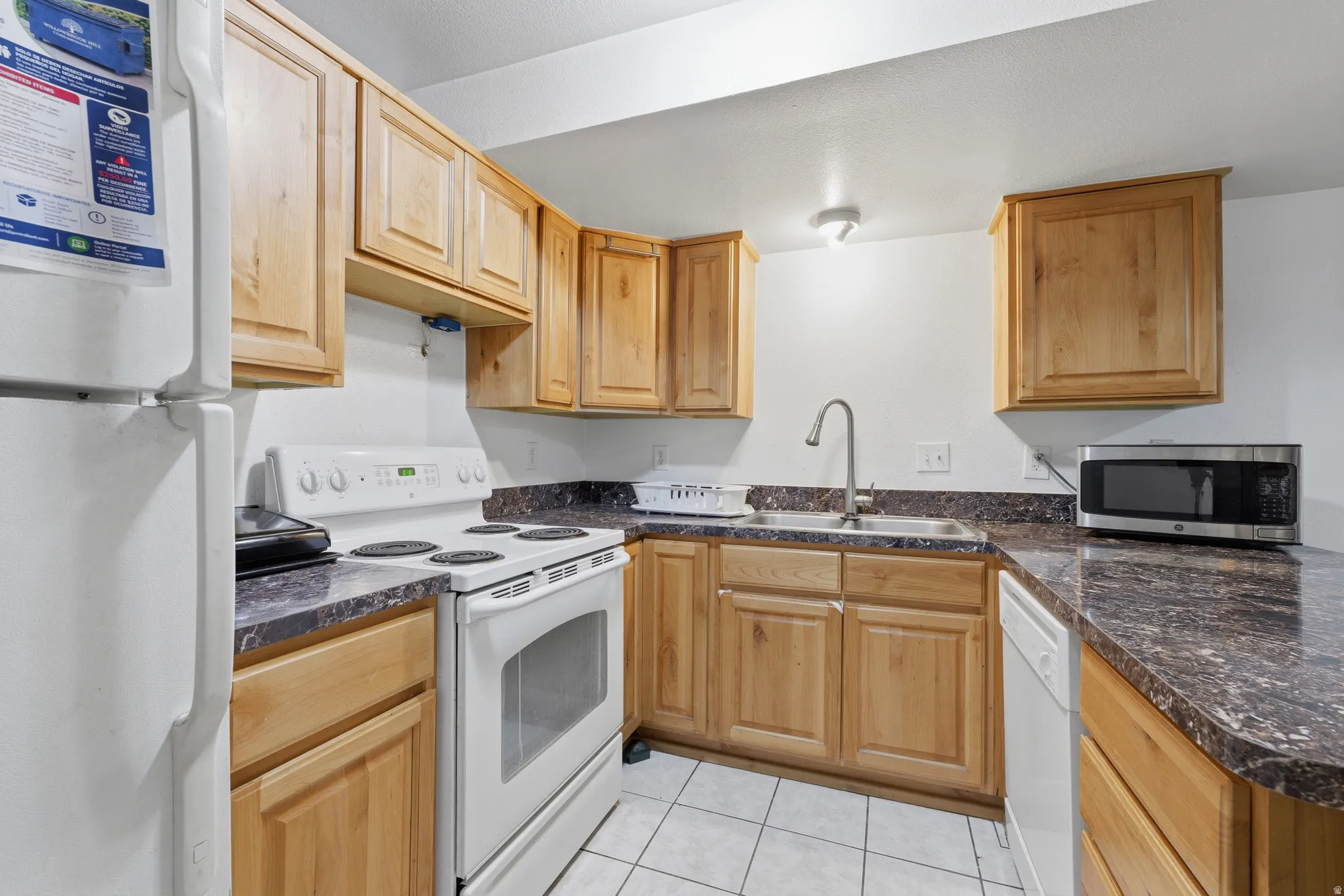 Kitchen featuring wood-finish cabinetry, dark speckled countertops, and tile flooring