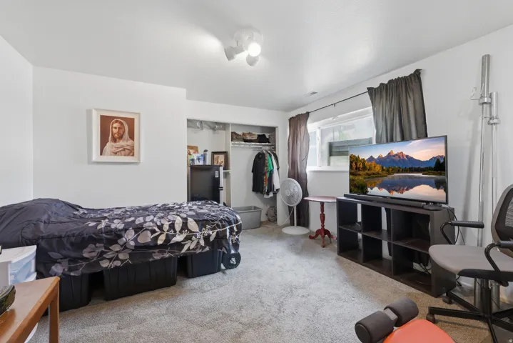 Carpeted room with white walls, a single window with dark drapes, and an open closet