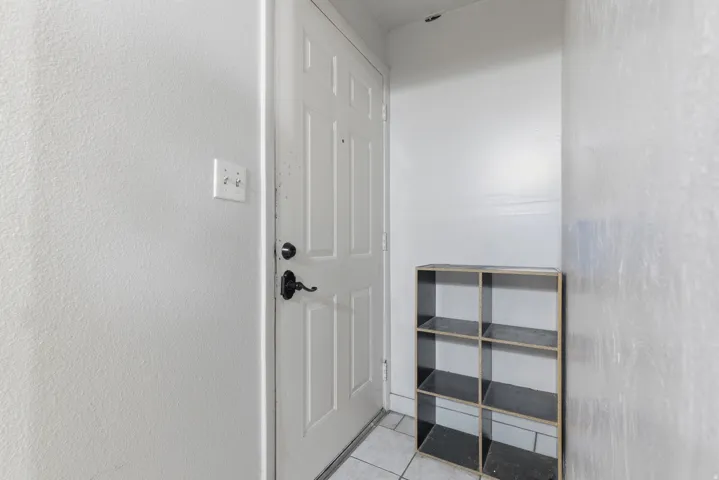 Entryway featuring a paneled door with dark hardware, light-colored walls, and tile flooring