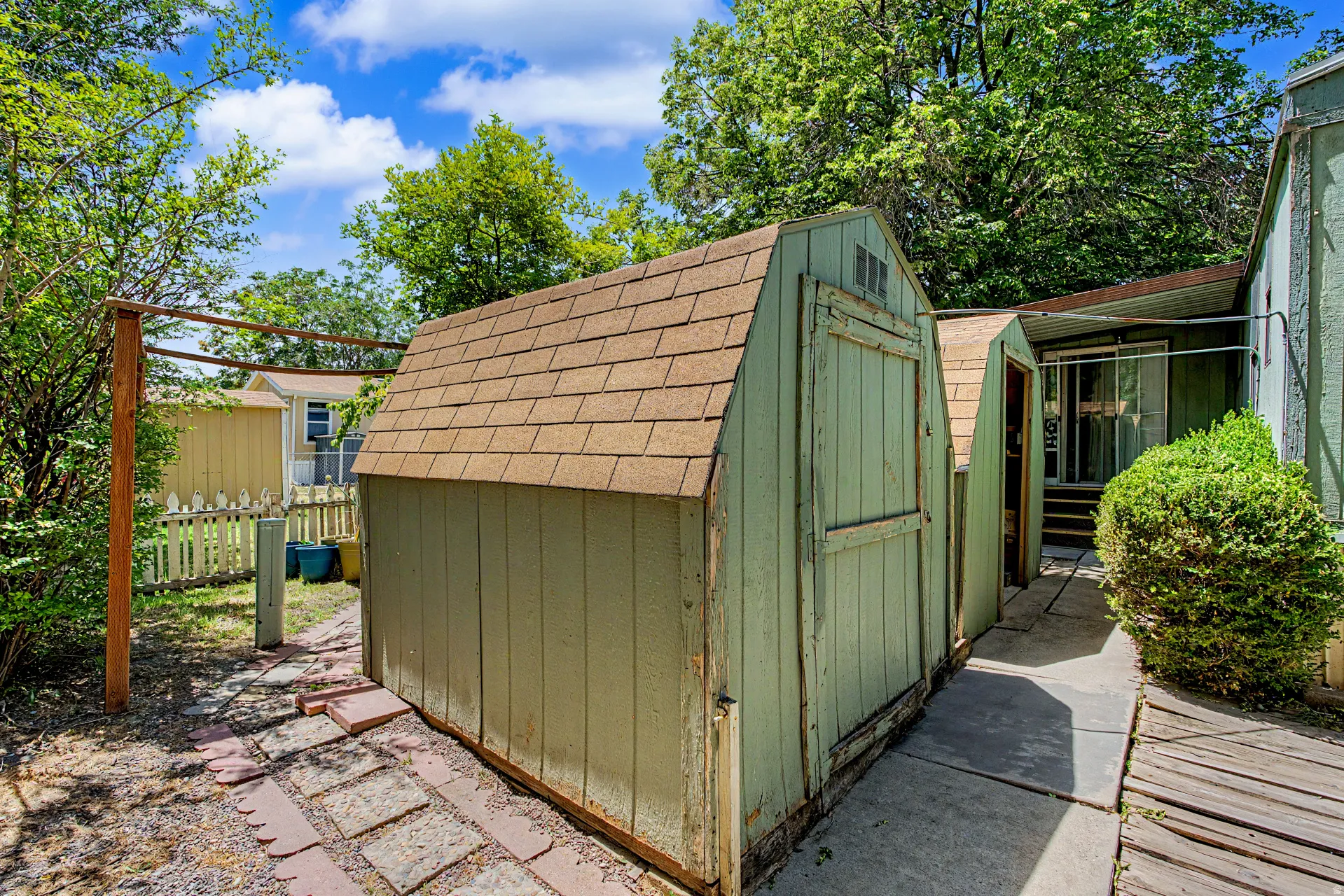 Two outdoor storage sheds featuring wood siding and shingle roofs