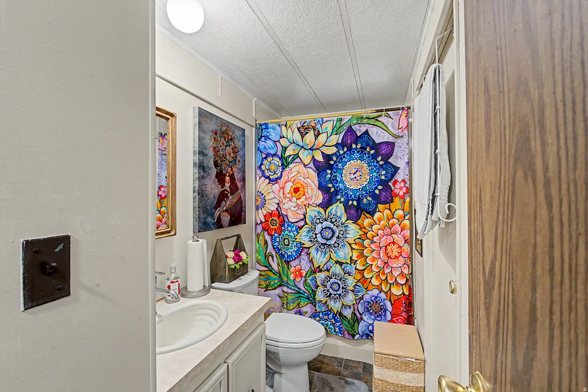 Bathroom featuring a single vanity with an integrated sink, a toilet, and a shower area with a curtain rod