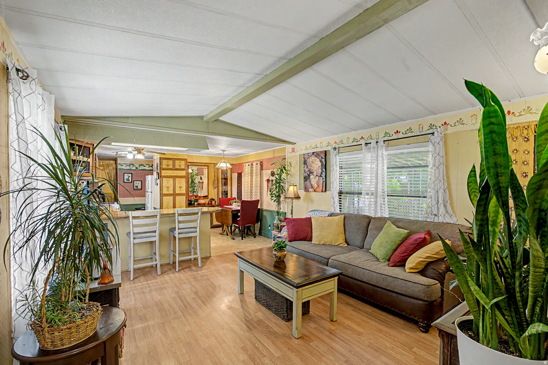 Open concept living area featuring wood-finish flooring, a breakfast bar with seating for two, and multiple windows with blinds
