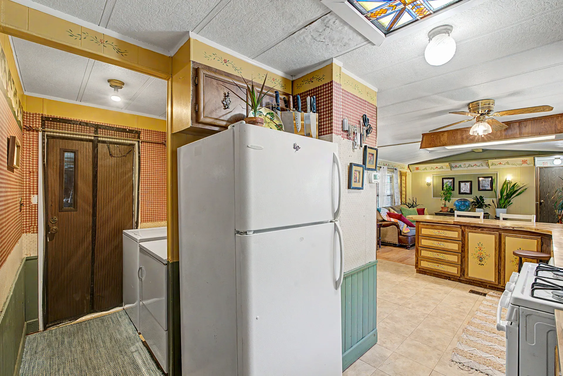 Spacious kitchen featuring a white top-freezer refrigerator, built-in cabinetry, and a large central island with seating
