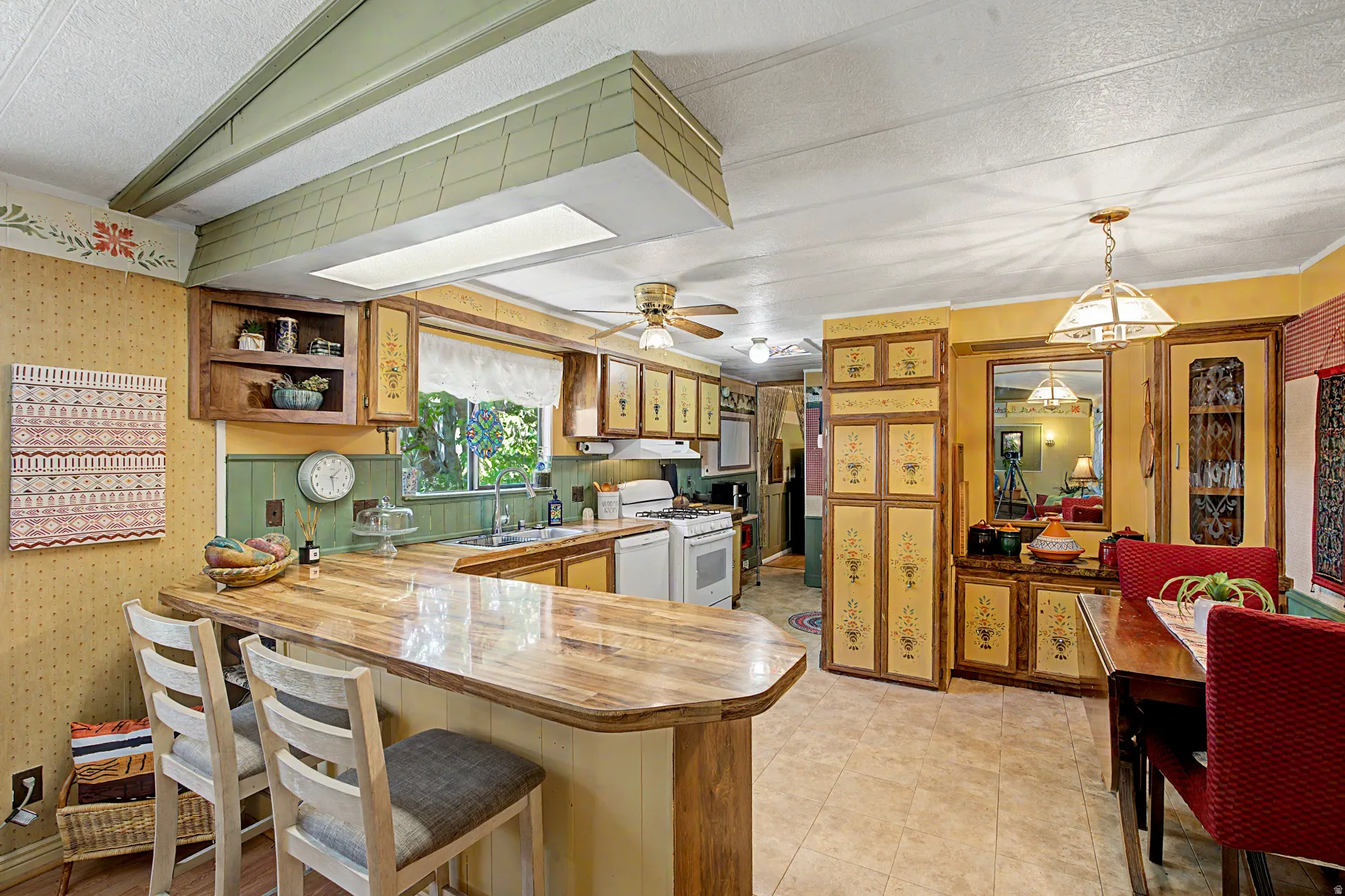 Kitchen featuring a built-in breakfast bar with a wood-finish countertop, white appliances, and a double basin sink