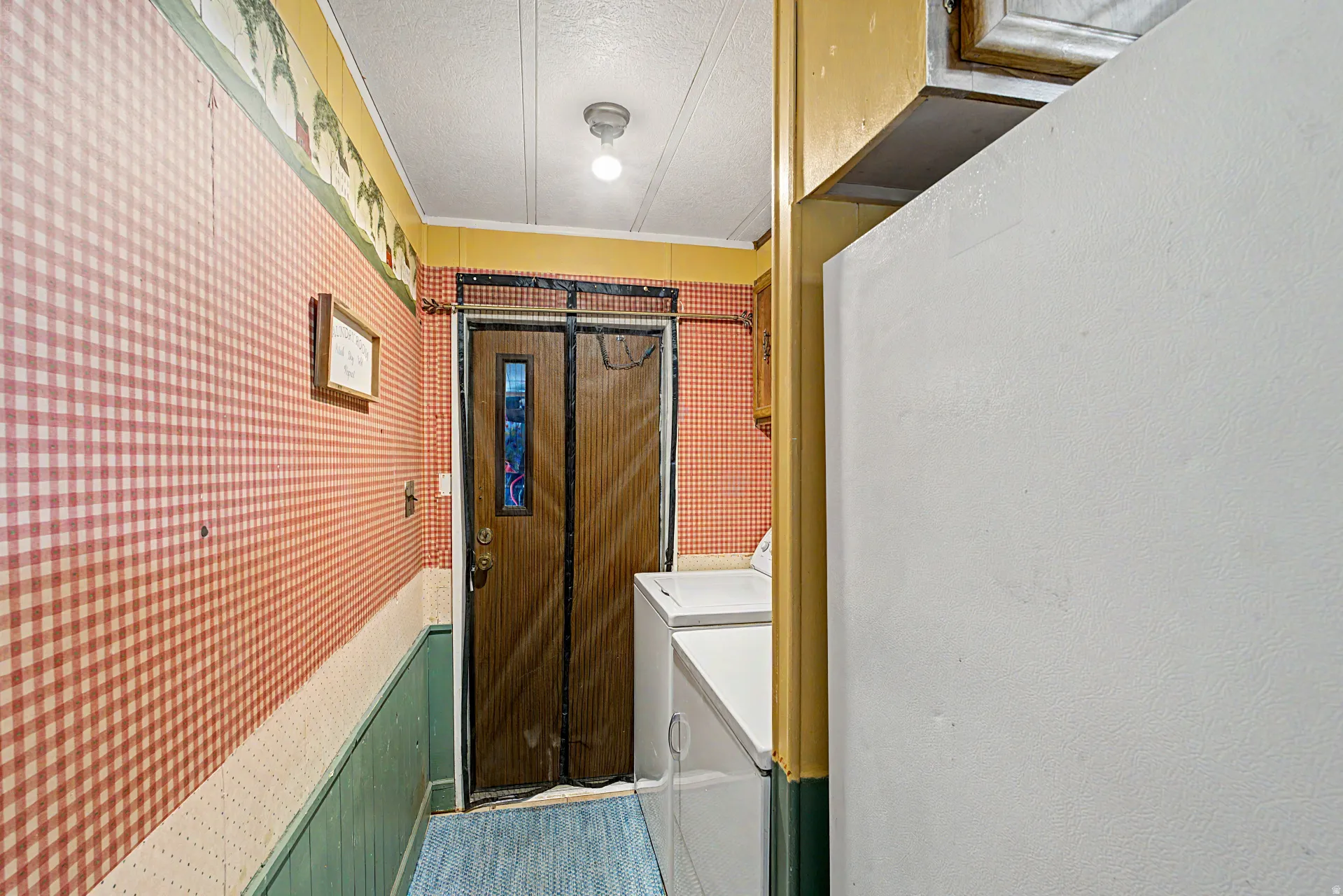 Compact utility space featuring a paneled wood door with a window, a single overhead light fixture, and a white countertop
