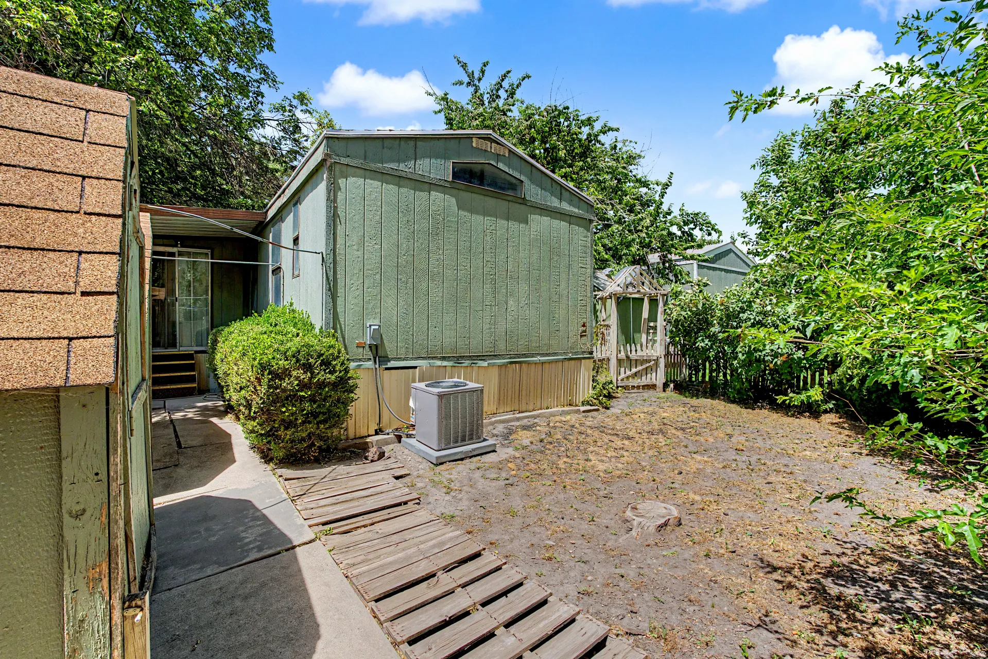 Spacious backyard area featuring a wooden picket fence, lush perimeter foliage, and a garden gate
