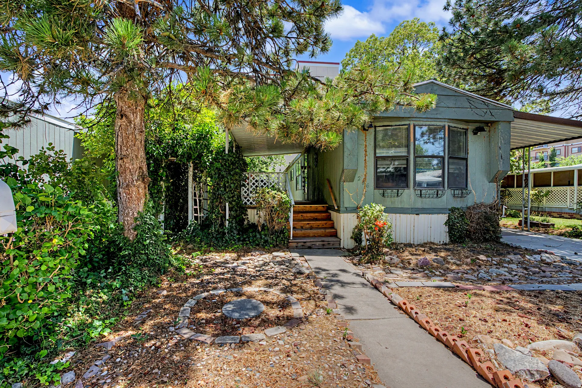 Single-story residence featuring a bay window, covered entry porch with wood steps, and a carport