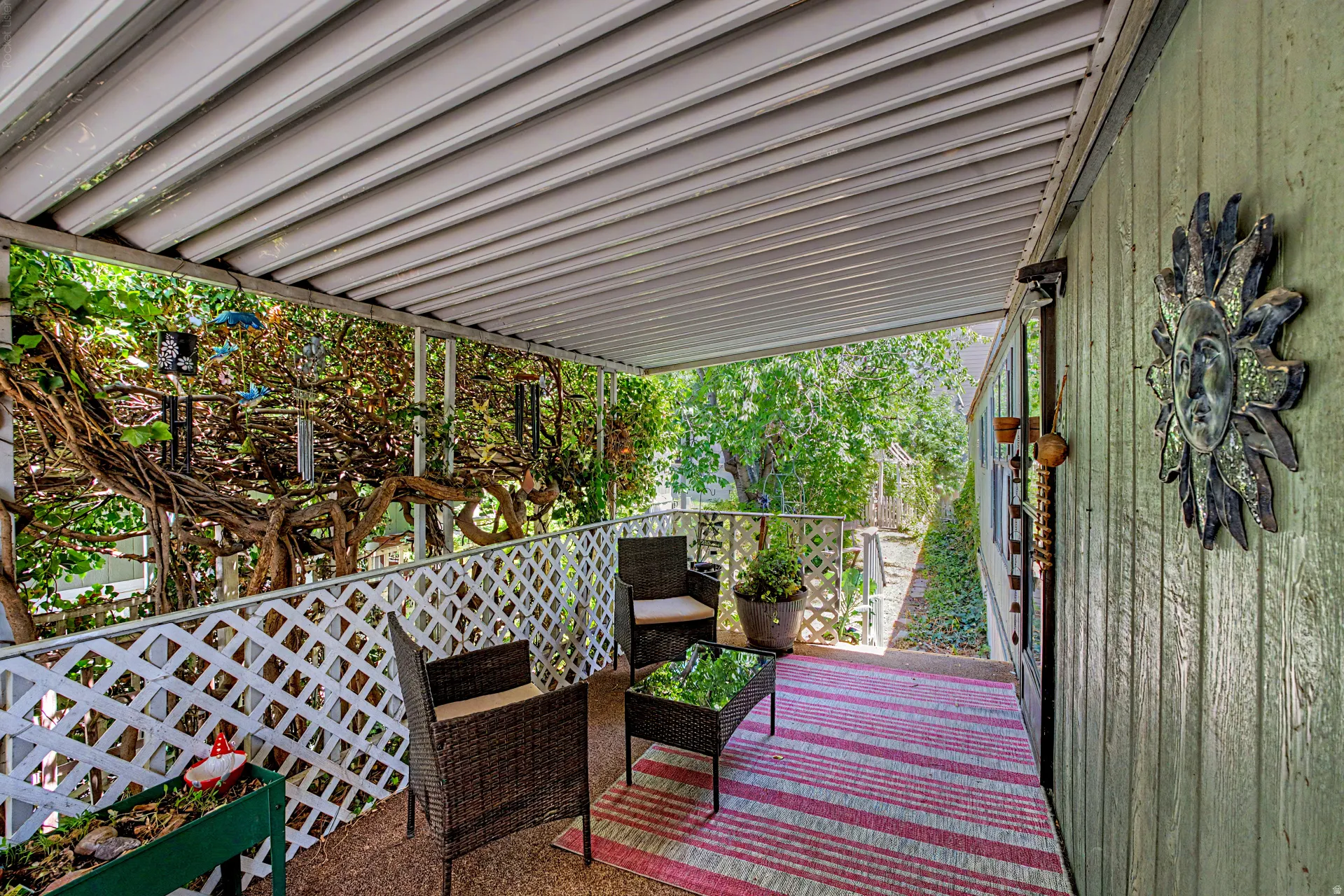 Covered patio featuring a slatted white ceiling and white lattice railing