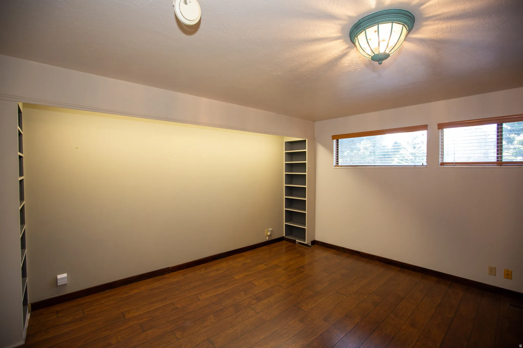 Primary Suite featuring wood-finish flooring, two windows with blinds, and built-in shelving