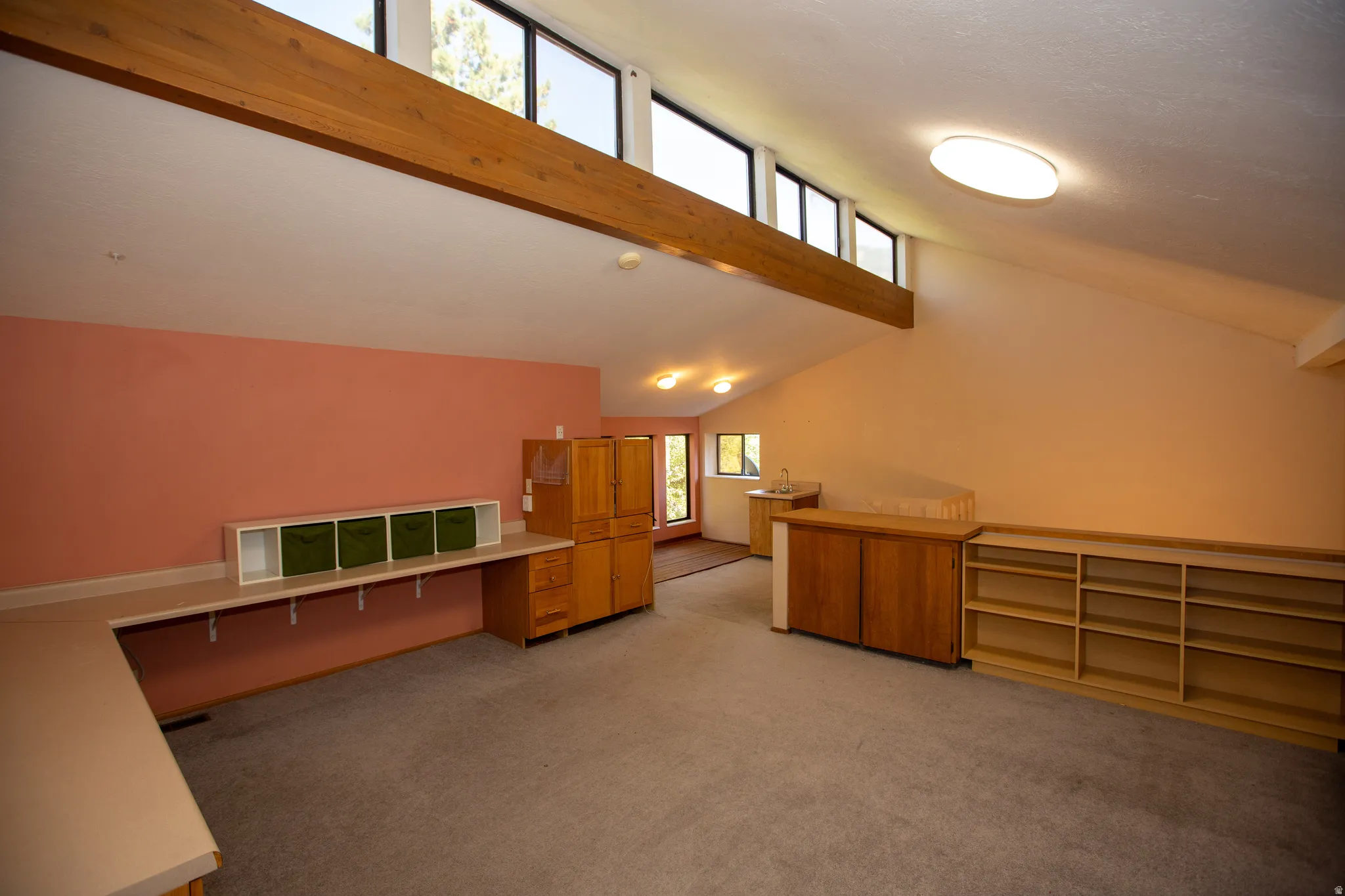 Vaulted ceiling with clerestory windows, built-in shelving, and a wood beam accent