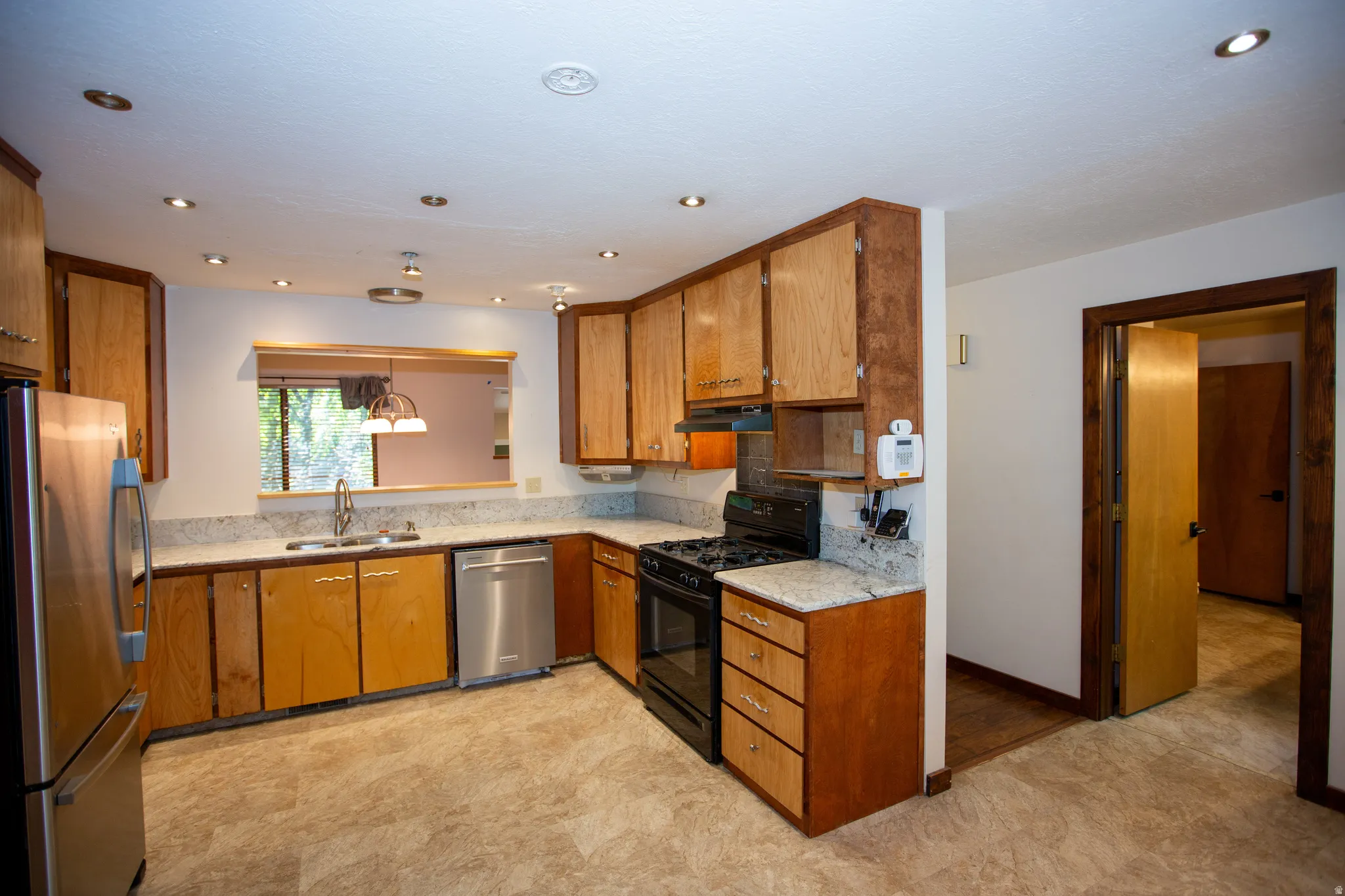 Kitchen featuring light wood cabinetry, granite countertops, and stainless steel appliances including a refrigerator and dishwasher