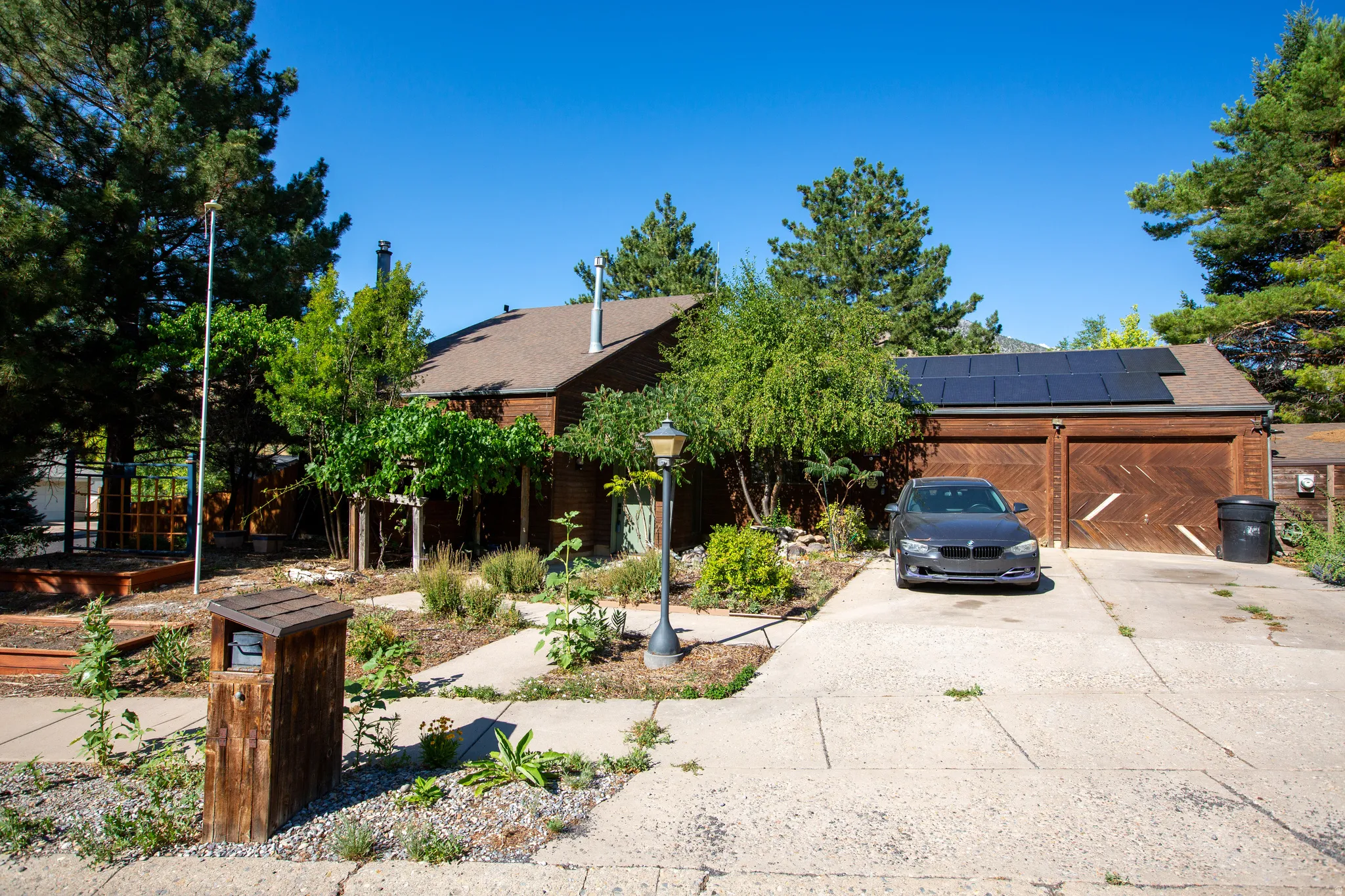 Brown-sided residence featuring a two-car garage with wood-finish doors and rooftop solar panels