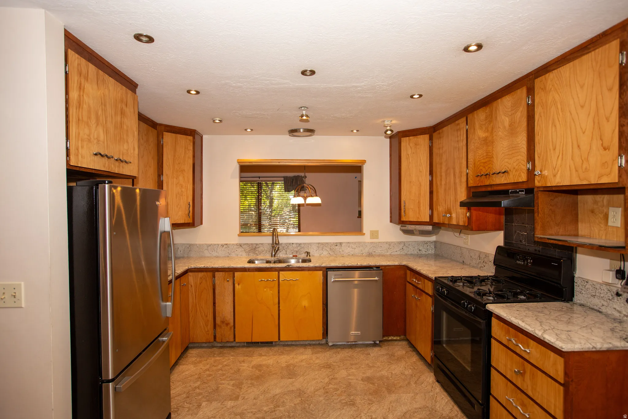 U-shaped kitchen featuring wood cabinetry, granite countertops, and recessed ceiling lighting