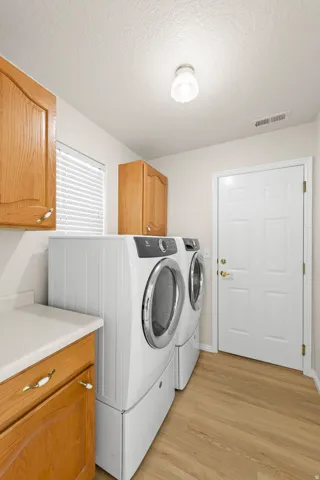 Utility room featuring wood-finish flooring, light-colored cabinetry with decorative hardware, a built-in countertop, a window with blinds, and a white paneled door