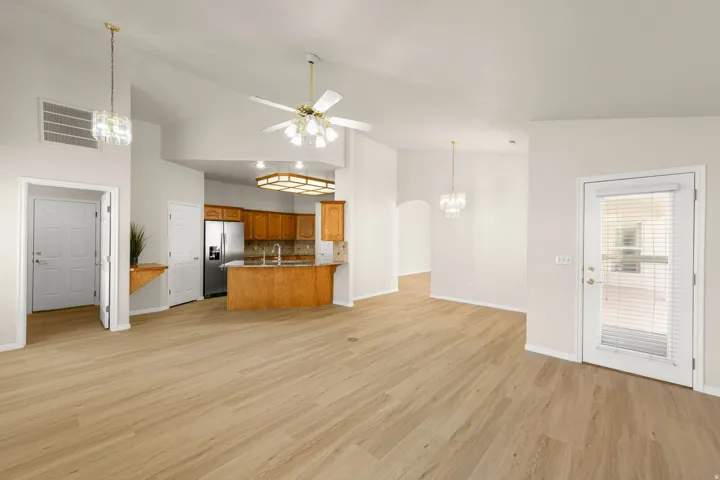 Open-concept living area featuring wood-finish flooring, vaulted ceilings, and a kitchen with wood cabinetry