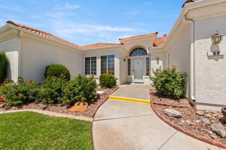 Exterior featuring stucco finish, a tile roof, an arched entry, and a concrete pathway