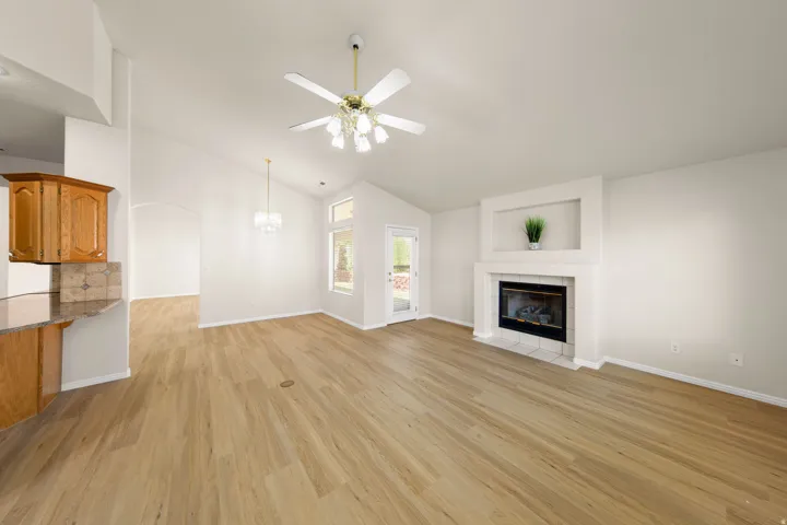 Spacious living area featuring wood-finish flooring, a white fireplace with an integrated niche, and vaulted ceilings
