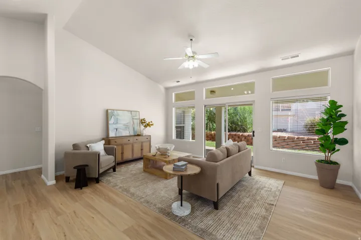 Vaulted ceiling, wood-finish flooring, sliding glass door, transom windows, and a ceiling fan