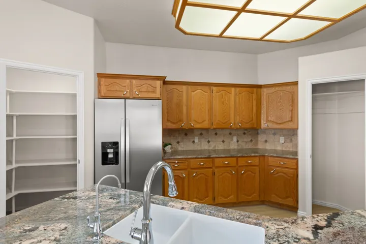 BRAND NEW STAINLESS APPLIANCES - Kitchen featuring a double basin sink, granite countertop, stainless steel refrigerator, wood cabinetry, and a tile backsplash