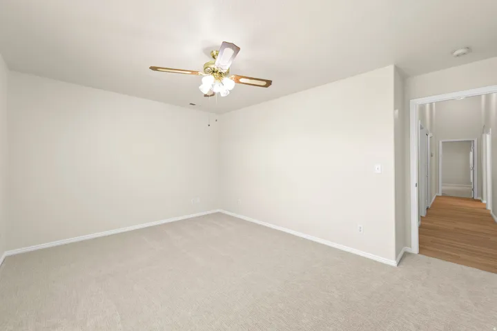 GUEST BEDROOM 1 - Carpeted room featuring a ceiling fan with integrated lighting, neutral wall tones, and white baseboards