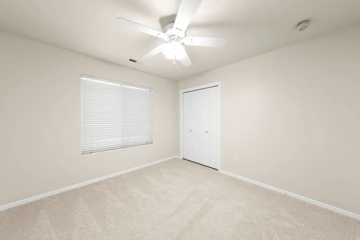 GUEST BEDROOM 2 - Carpeted room featuring a ceiling fan with integrated lighting, a window with horizontal blinds, a bi-fold closet, and baseboard trim