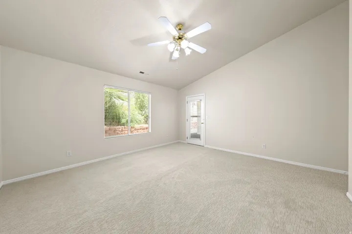 PRIMARY SUITE - Vaulted ceiling with a ceiling fan, recessed window with blinds, and light-toned carpet flooring